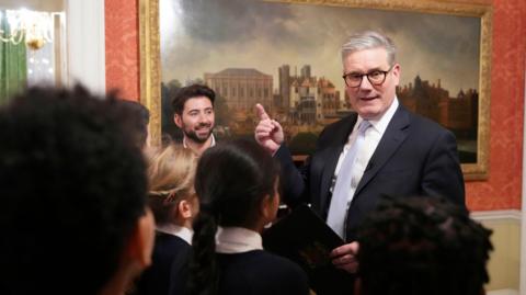 Prime Minister Keir Starmer points at an old painting in front of a group of children