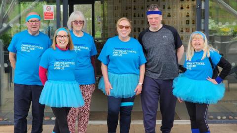 Walking group wearing blue t-shirts and tutus