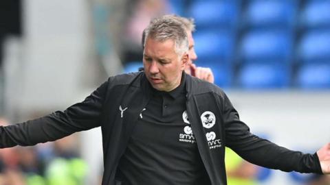 Darren Ferguson holding his arms up on the touchline