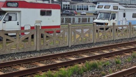 Two camper vans parked on a road next to a tramline