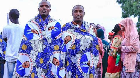 Two men who support Paul Biya wrapped in blue-patterned cloth with the face of Cameroon's president - Yaoundé, Cameroon
