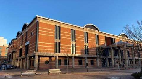 Teesside Crown Court in Middlesbrough. It is three storeys high with red bricks and large long dark windows.