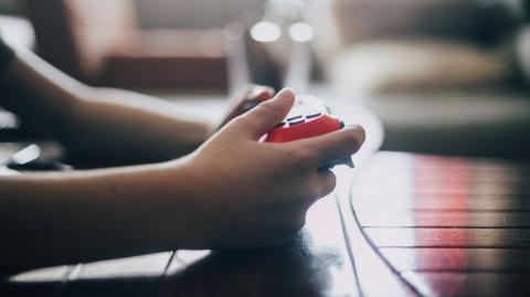 Close up of boy holding game controller.