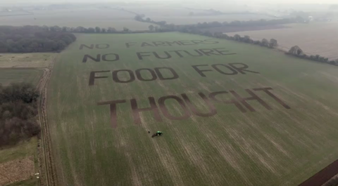 A green field in Berkshire with the words "No farmers, no future, food for thought" carved by farmer George Brown