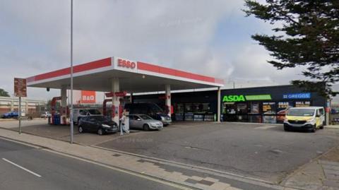 Esso garage forecourt with several cars at the pumps.