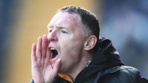 Graham Coughlan with his right hand cupped to his mouth to shout at his players from the touchline