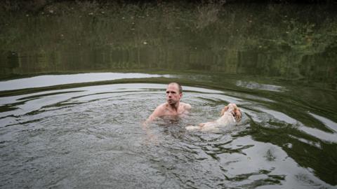 Man with a dog swimming in a river.