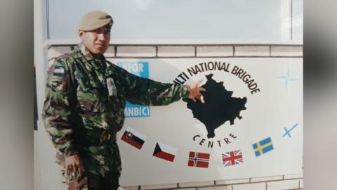 A man in a military uniform standing next to a signpost.