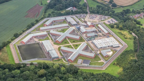 Aerial shot of Lowdham Grange prison - a series of modern buildings set in countryside