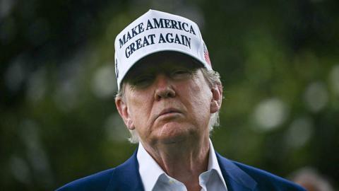 Trump wearing a white MAGA hat.