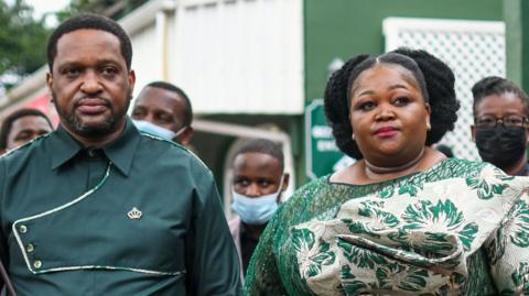 A head and shoulder shot of the Zulu king and his first wife wearing matching formal bottle green outfits. 