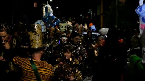 Group of people playing brass instruments, surrounded by Halloween theme lanterns.
