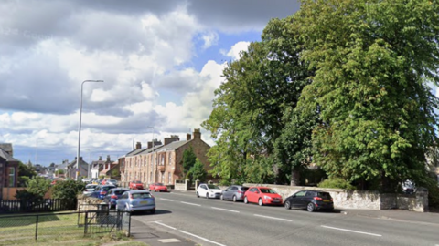 A general view of Haddington Road in Tranent. There are houses, trees and cars parked along the road. 