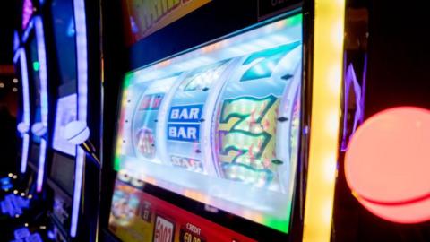 We can see the screen of a digital slot machine. It's displaying a traditional style game with three reels where we can see the number 7 and 'Bar'.