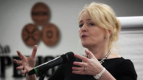 Unite general secretary Sharon Graham speaks into a microphone with both of her hands raised to her shoulders