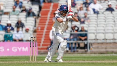 Ben Geddes hits a shot with his Gray-Nicolls bat and watches it down the leg side wearing his Middlesex whites with the county logo on his right thigh.