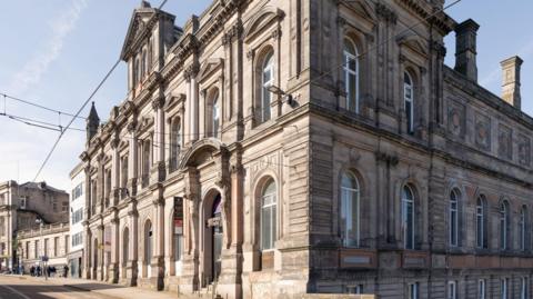 A large building made from stone next to tram tracks