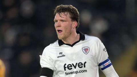 Rob Dickie standing on the pitch during a match looking to his right midway through talking
