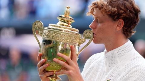Jannik Sinner kisses the Wimbledon trophy