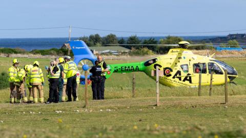 Helicopter on field with police officers nearby