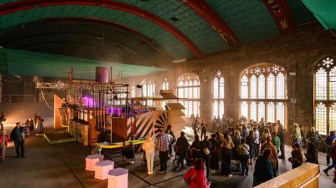 Picture of an exhibtion in Blackburn, set inside a church. An art installation is seen with several people milling around it.
