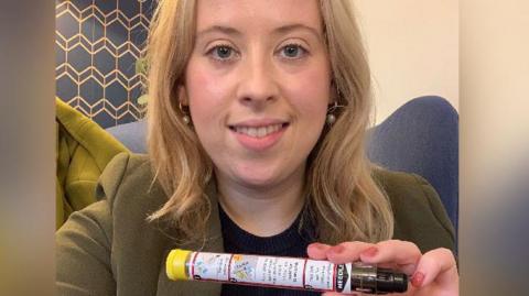 Becky Gittins, an MP, holds an adrenaline pen