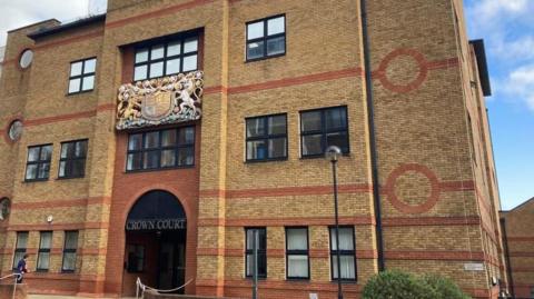 St Albans Crown Court: A building made of brown and red bricks. The words "CROWN COURT" are written above the entrance.