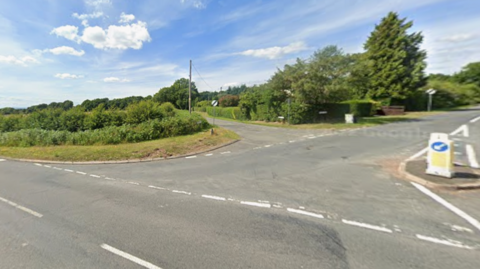 A road junction going off into three roads, with lots of bushes lining the roads.