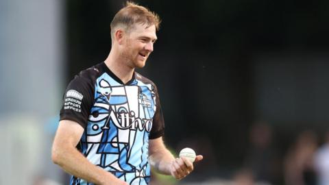 Worcestershire's Tom Taylor inspects the ball as he turns to start his run up