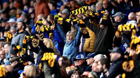 Sheffield Wednesday fans raise black and gold scarves to protest against the club's owner