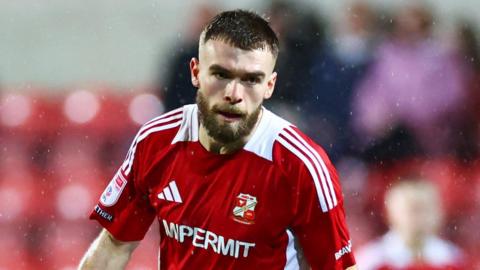 Aaron Drinan running with the ball at his feet during a match for Swindon