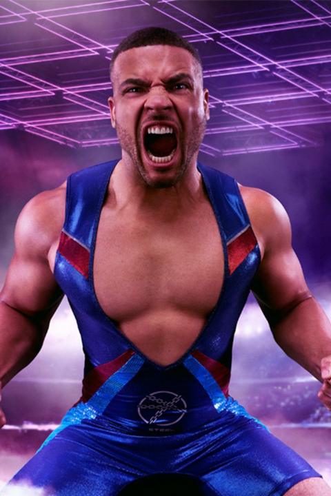 A man flexes his muscles in a tight leotard which is open at the chest