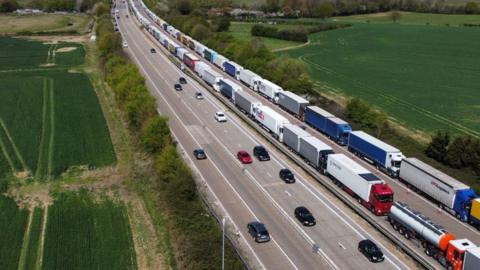 Lorries queue on one side of the M20 motorway while cars pass on the other side