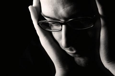 Man with head in his hands holding his ears