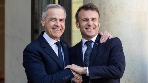 French President Emmanuel Macron (R) shakes hand with Canadian Prime Minister Mark Carney (L) at the Elysee Palace in Paris