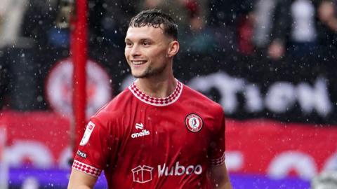 Luke McNally smiling and jogging behind the goalposts after scoring a goal in December 2024