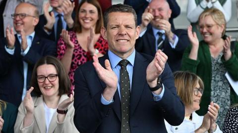 Rhun ap Iorwerth applauding on the steps of the Senedd building steps