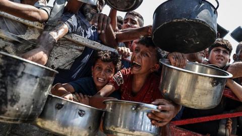Palestinians wait for food at a charity kitchen in Gaza City, northern Gaza (28 July 2025)