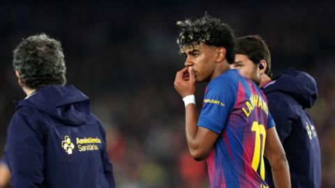 Lamine Yamal walks off the pitch, hand to his mouth, looking disappointed