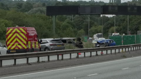 Cars by the roadside, with one burnt out