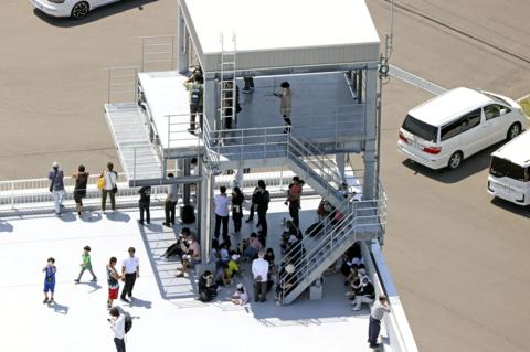 People evacuated are seen on the roof of the fire station building after Japan issued evacuation alert following major quake in Russia's Kamchatka Peninsula that triggered a tsunami warning, in Mukawa Town, Hokkaido, Japan July 30, 2025