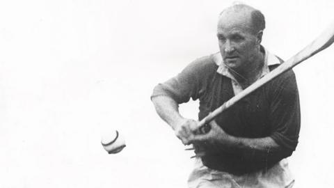 A black and white image of a man hurling. 