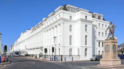 A computer-generated image of a large white regency-style building on a seafront in Eastbourne