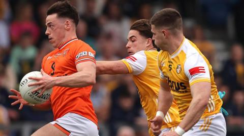 Armagh's Tomas McCormack attempts to break away from Antrim's Eoghan McCabe and James McAuley