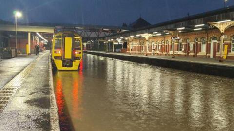 A train at flooded Wellington station. The train tracks are covered in floodwater