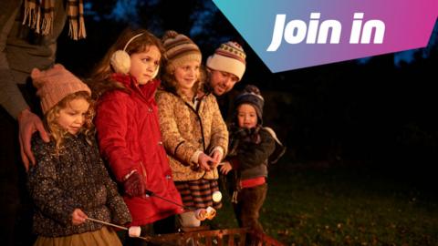 a group of children wearing warm winter clothes holding marshmallows over a fire