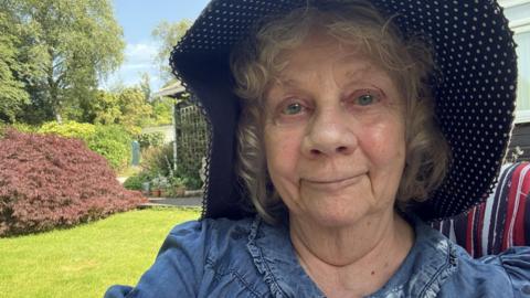 A selfie of a woman in a garden wearing a wide-brimmed hat.