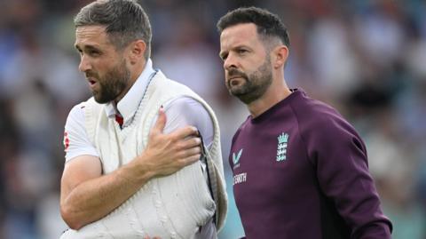 Chris Woakes holds his shoulder and walks off with it in a makeshift sling