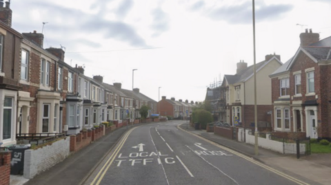 Two rows of terrace houses line Kent Street in Jarrow. They are made of red brick and have bay windows. 