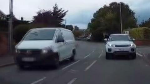A white van overtaking a white car on a residential street
